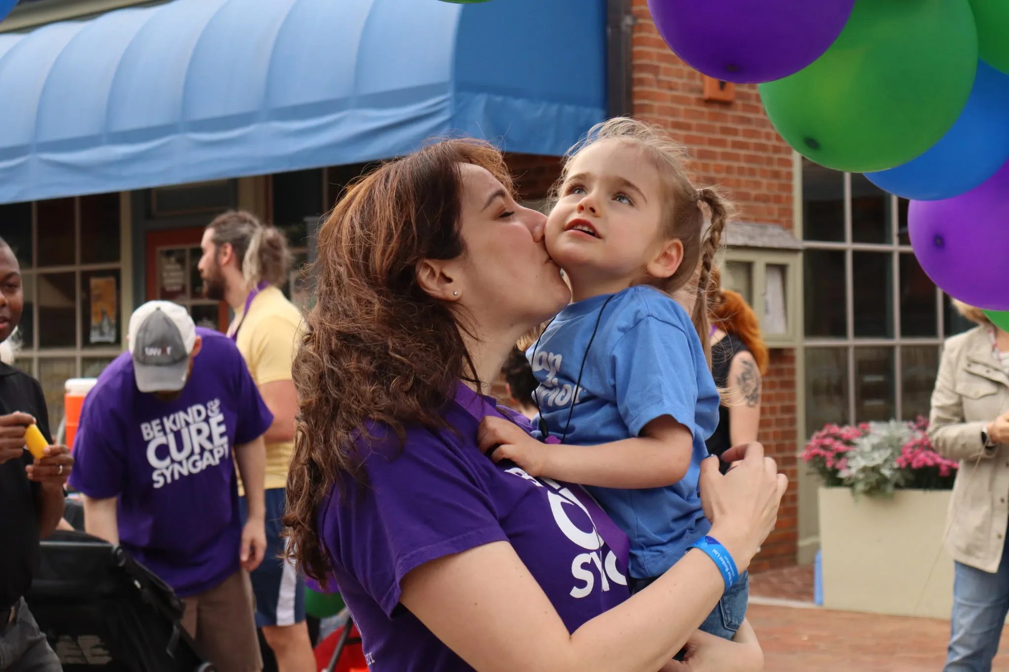 Sara Driscoll holding her daughter, Mora, at a SYNGAP1 community event